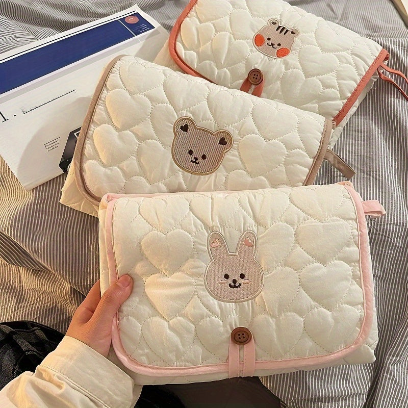 Portable changing mat with cream bear pattern, foldable, breathable polyester, adjustable strap, ideal for short trips.